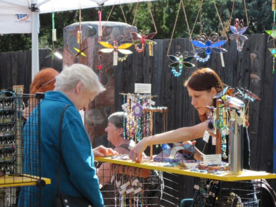 An artist spends time with a visitor, explaining their handmade items