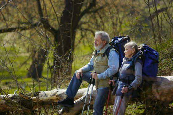 surrounded by nature aged family couple man woman tourist outfit walking green lawn near by trees sunny day concept tourism healthy lifestyle relaxation togetherness